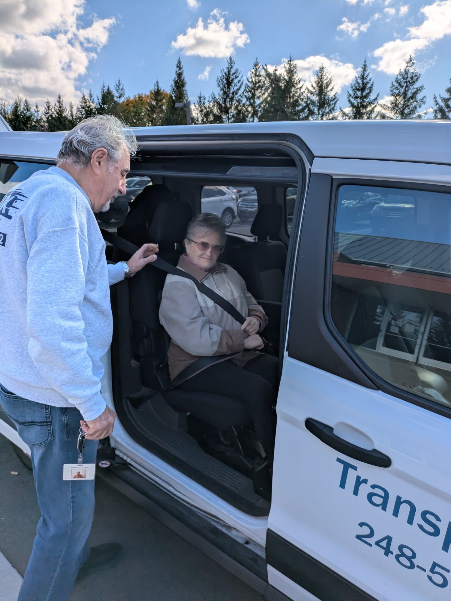 A driver helping an older adult into a Federation transportation services van